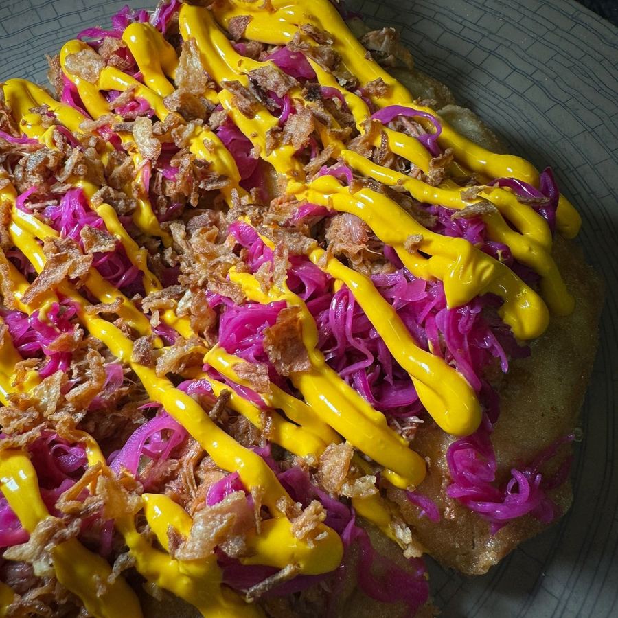 Pizza fritta aperta con pulled pork, verza rossa, cipolla croccante e salsa al cheddar.